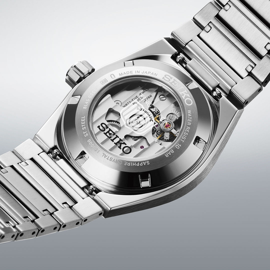 A close-up of the Seiko King Seiko Vanac Automatic with Manual Winding 41mm Watch displays its stainless steel band and transparent case back, revealing the intricate mechanical movement inside.