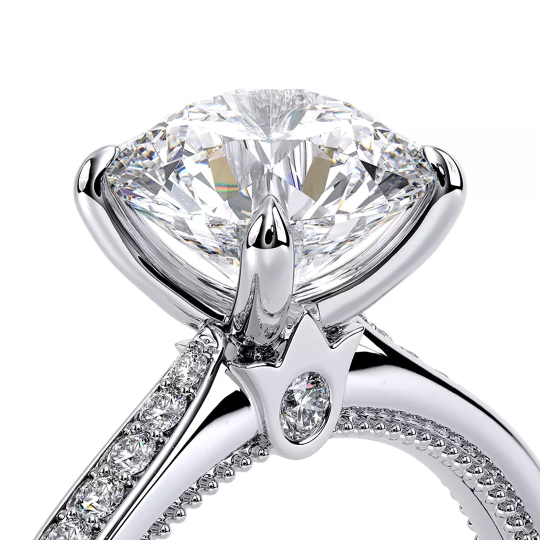 A close-up of the Verragio Renaissance 14K White Gold Round Brilliant Solitaire Lab Diamond Engagement Ring showcases an elegant design with a prominent clear diamond set in a four-prong arrangement. The band is embellished with smaller diamonds, enhancing the ring's sparkle and sophistication.