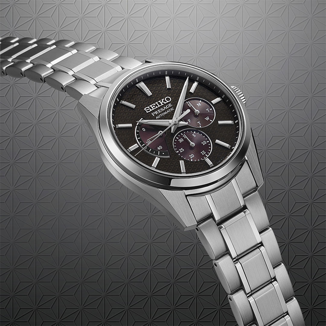 A Seiko Presage Sharp Edge Series Automatic Watch with a 40.2mm stainless steel band is showcased at an angle, featuring a dark textured face. The subtle geometric pattern in the background enhances the sophisticated look of this exemplary piece of Japanese craftsmanship by Seiko.