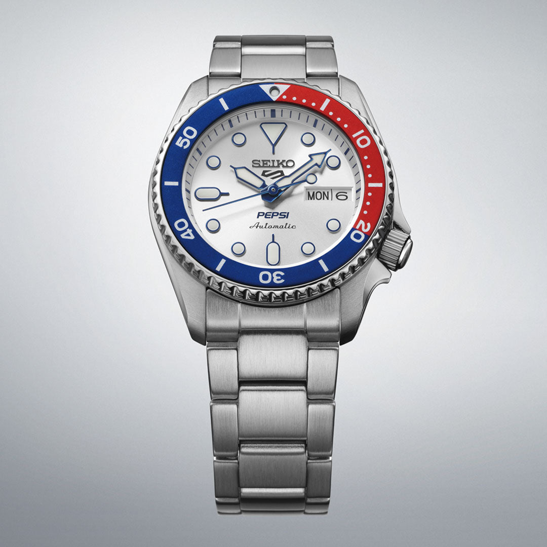 The Seiko 5 Sports SKX Series Pepsi Automatic 38mm Watch is a limited edition of 7,000 pieces, featuring a silver metal band, white dial, blue and red bezel, and day-date display.