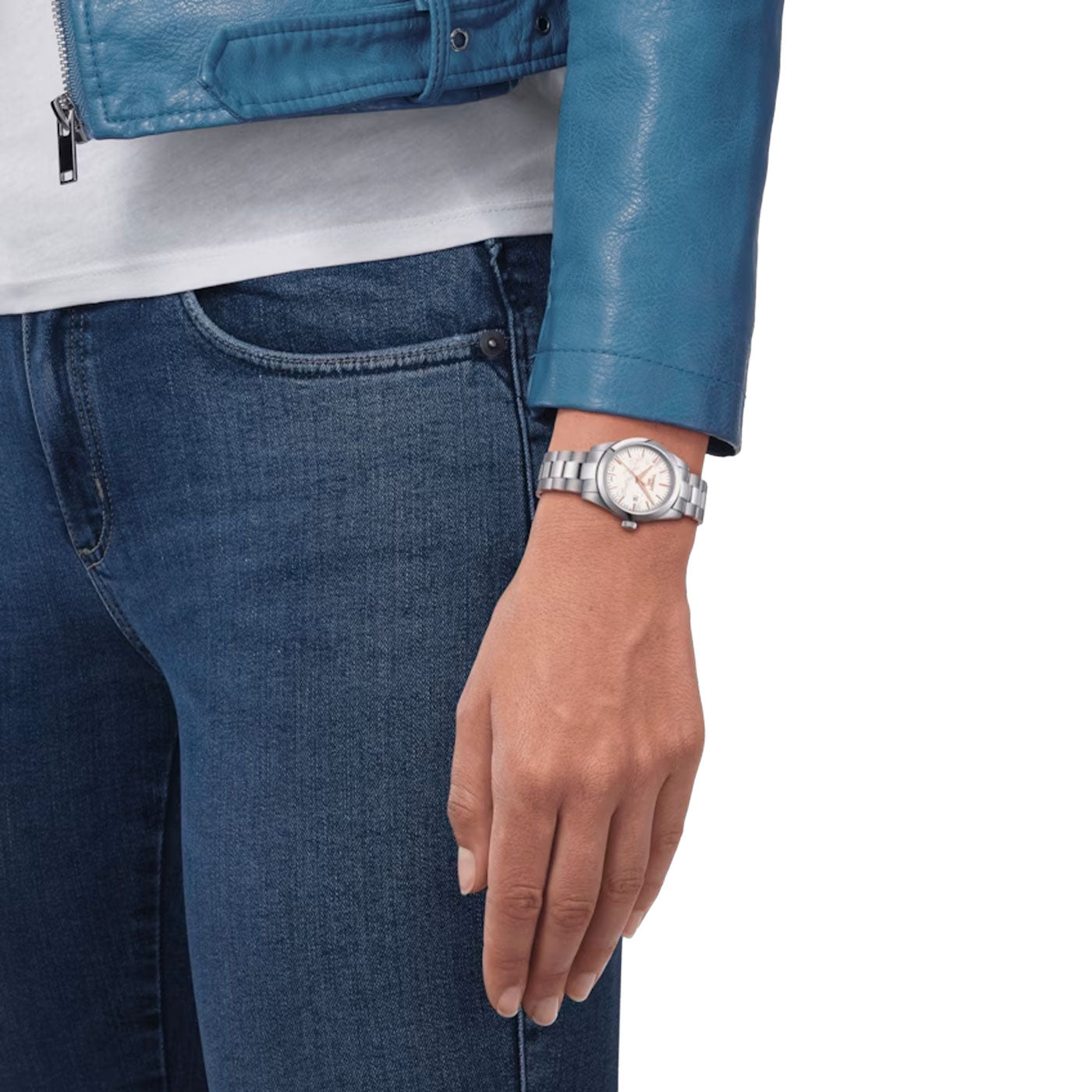 A person wearing a blue leather jacket and jeans stands with their hand at their side, showcasing the elegant Tissot T-My Lady Quartz 29mm Watch on a sleek silver metal band. The plain white background enhances the ensemble, creating an effortlessly stylish image—feel free to share it!