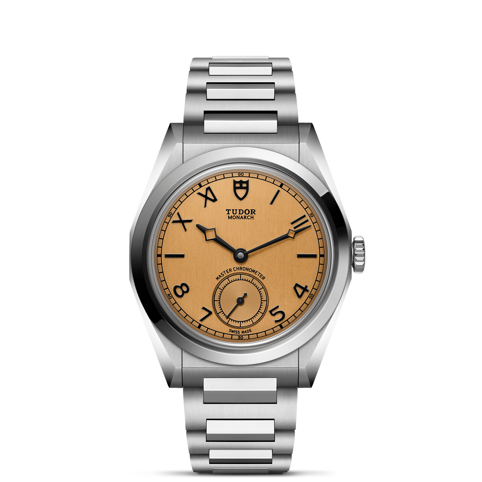 The TUDOR Monarch features a stainless steel case, light brown dial with black Arabic numerals, small seconds at 6 o’clock, and a brushed metal bracelet. The iconic TUDOR logo is positioned below 12 o’clock.