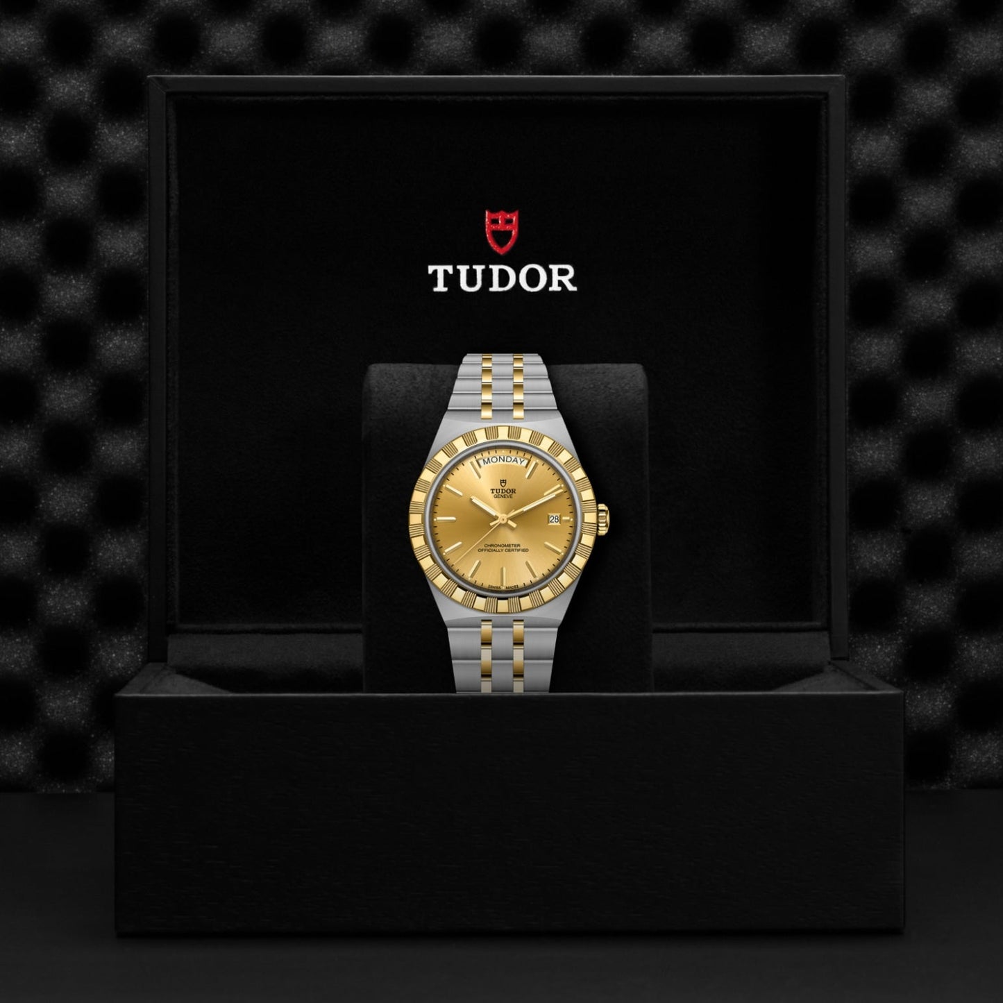 The TUDOR Royal by TUDOR, featuring a gold dial and bezel, is presented upright in a black box with the Tudor logo on the inside lid, showcasing its sport-chic elegance.