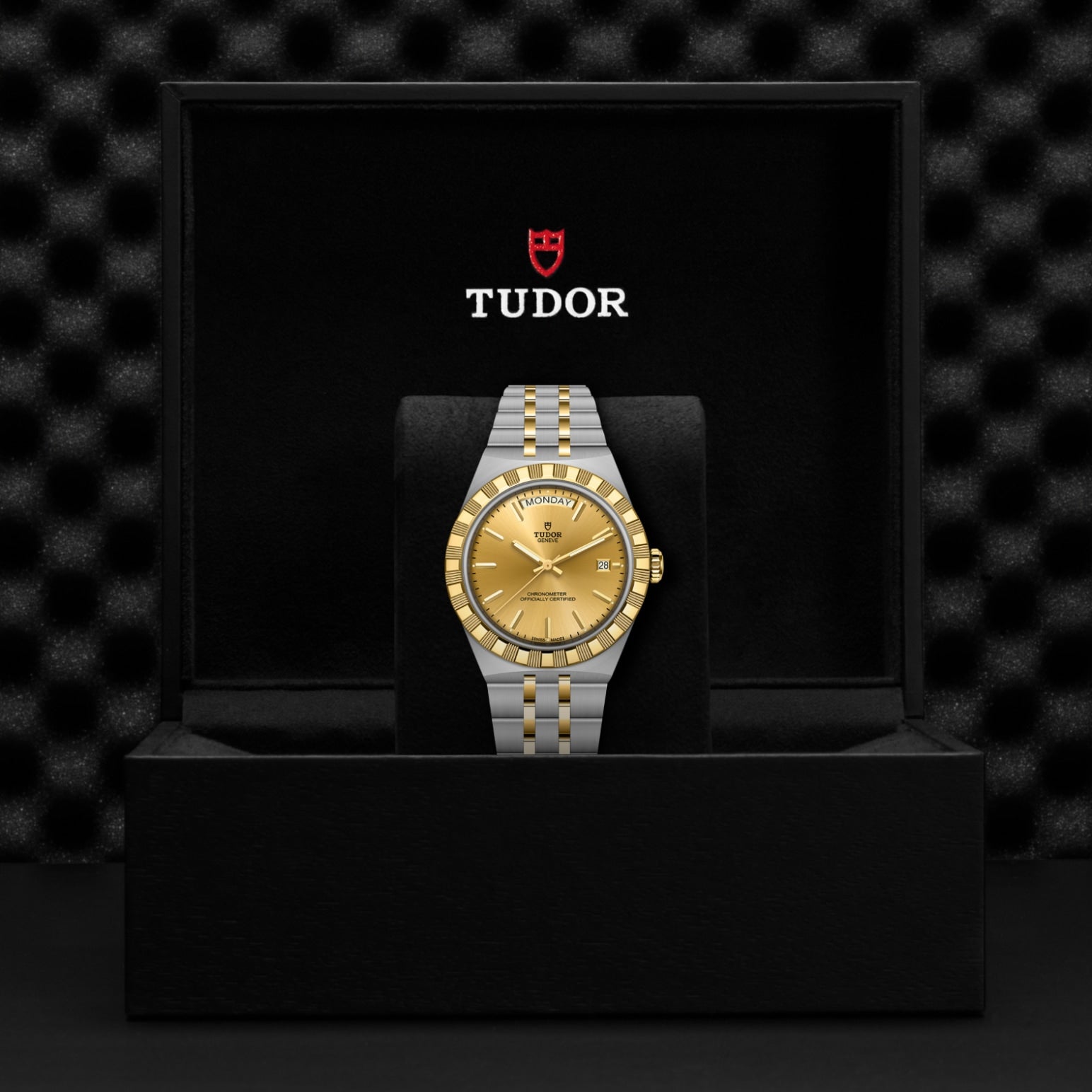 The TUDOR Royal by TUDOR, featuring a gold dial and bezel, is presented upright in a black box with the Tudor logo on the inside lid, showcasing its sport-chic elegance.
