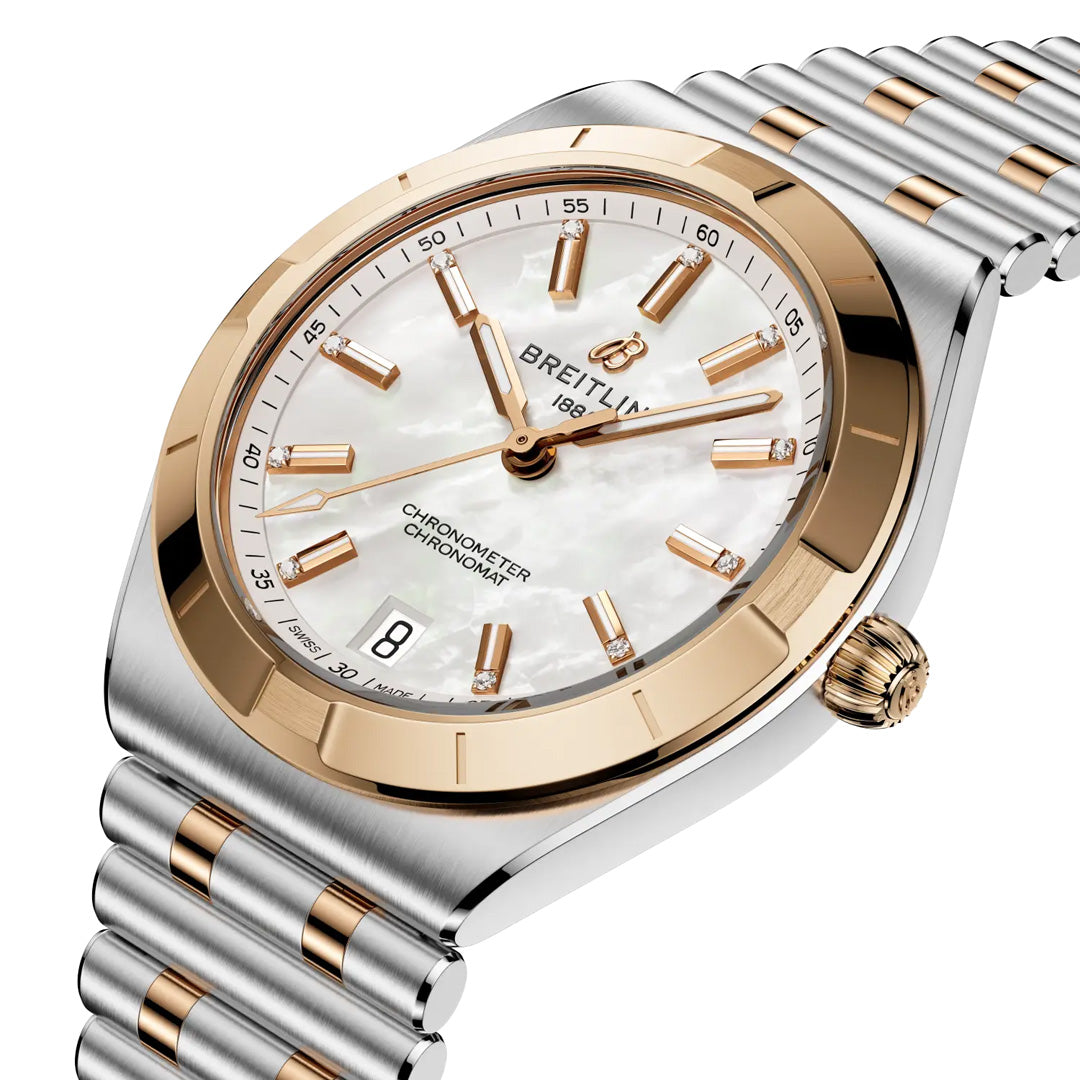 The BREITLING Chronomat Automatic 36 is a luxury sports watch featuring a silver and gold metal band, white mother-of-pearl dial, gold hour markers and bezel, date at 6 o’clock, and COSC-certified automatic movement.