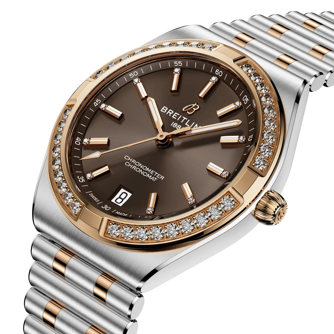 The BREITLING Chronomat Automatic 36 is a luxury sports watch featuring a brown dial, gold markers, date window, diamond-studded gold bezel, two-tone silver and gold bracelet, and COSC-certified precision.