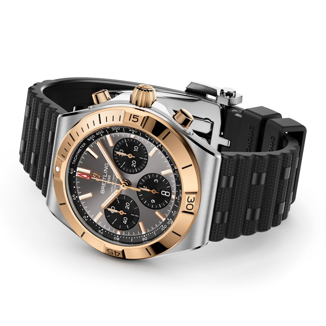 The Breitling Chronomat B01 Chronograph 42 features a black textured rubber strap, stainless steel and gold bezel, and a black dial with three subdials plus gold-tone hands and hour markers.