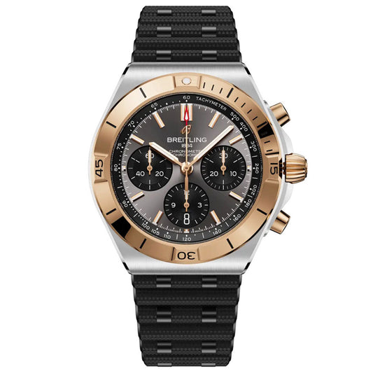 The BREITLING Chronomat B01 Chronograph 42 features a black textured strap, black dial, three chronograph subdials, gold-tone bezel, gold crown and pushers, plus white and red accents with a tachymeter scale.