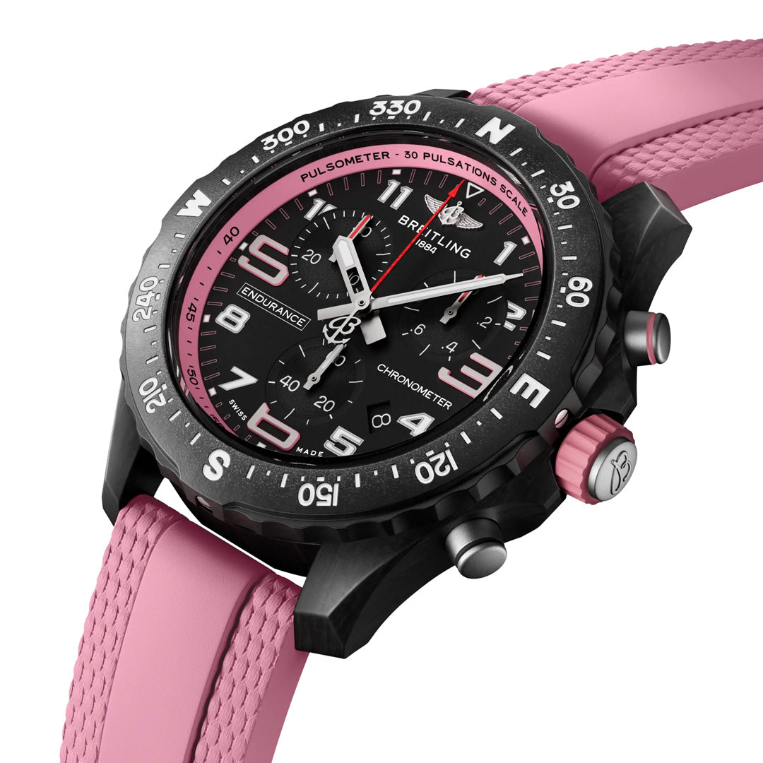 The BREITLING Endurance Pro 38 is a sporty black and pink watch featuring a pink rubber strap, durable Breitlight® case, large black dial with white and pink accents, multiple subdials, tachymeter scale, bold numbers, and a black bezel with engraved markings, ideal for an athleisure style.