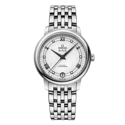 The OMEGA De Ville Prestige Co-Axial Chronometer 32.7mm watch offers a refined silver design with a stainless steel bracelet. Its round face is adorned with Roman numerals and a date window positioned at six o'clock, enhanced by an intricate patterned white dial. The addition of black hands contributes to its classic charm.