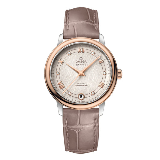 The OMEGA De Ville Prestige Co-Axial Chronometer 32.7mm Watch by OMEGA showcases a luxurious design with a silver dial and rose gold bezel. It features Roman numeral hour markers and a date display at six o'clock, exuding classic elegance with its brown leather strap that boasts a crocodile pattern for timeless sophistication.