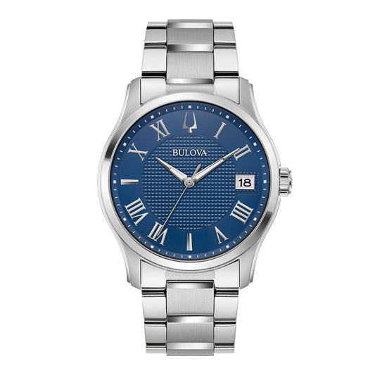 The Bulova Wilton Classic Quartz 41mm Watch showcases a blue dial adorned with Roman numerals and a date display. This timepiece highlights a stainless steel link band and a round dial, featuring intricate craftsmanship at its center.